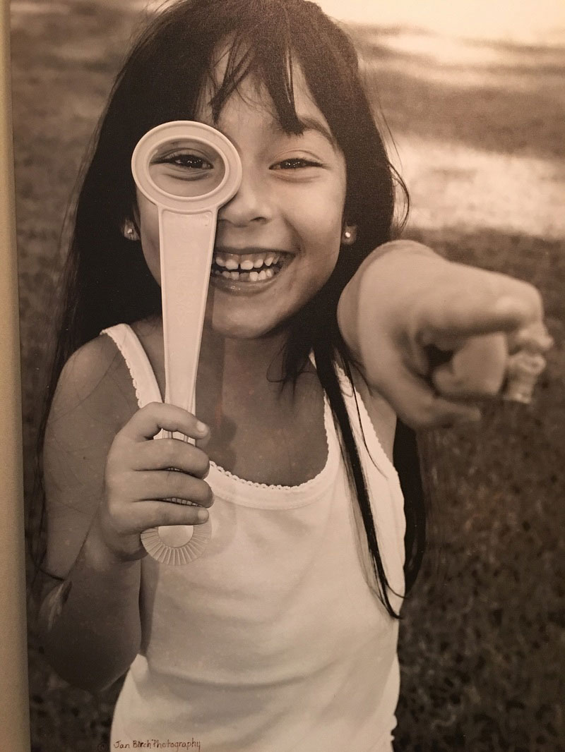 Girl looking through magnifying glass and pointing