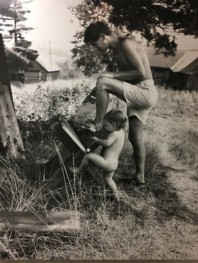 Man and naked boy outside cutting wood