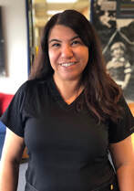 Monica Barrera smiling at camera and wearing black scrub top